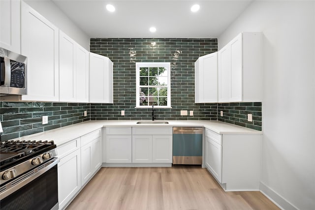 2012 Chew St, Houston, TX 77020 - kitchen featuring appliances with stainless steel finishes, light wood-type flooring, backsplash, white cabinets, and recessed lighting