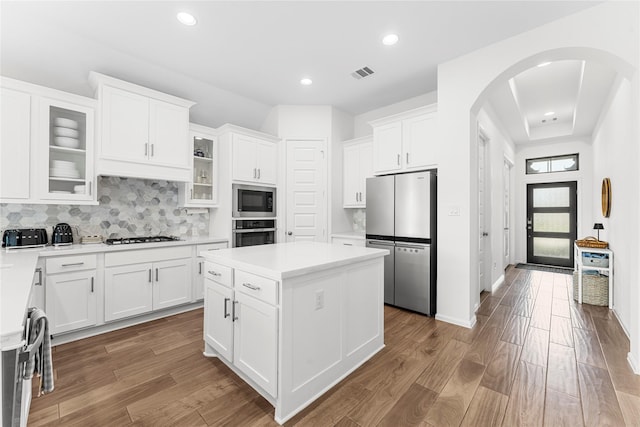 7202 Cordgrass Prairie Ln, Katy, TX 77493 - kitchen featuring arched walkways, stainless steel appliances, a kitchen island, tasteful backsplash, and light countertops