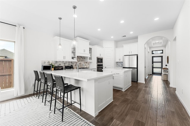 7202 Cordgrass Prairie Ln, Katy, TX 77493 - kitchen with arched walkways, a peninsula, stainless steel appliances, decorative backsplash, and recessed lighting