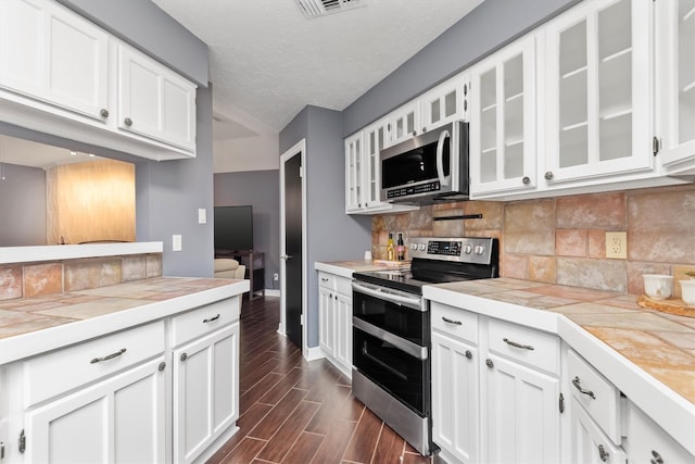 6510 Barrygate Dr, Spring, TX 77373 - kitchen featuring stainless steel appliances, white cabinetry, tasteful backsplash, a textured ceiling, and lofted ceiling