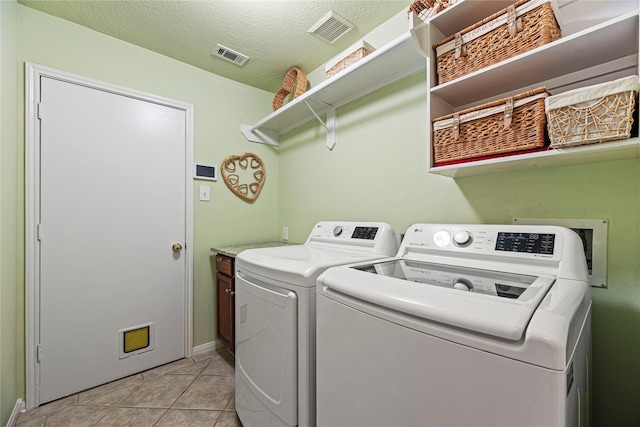 2218 Lashley Ct, Katy, TX 77450 - laundry area featuring cabinet space, washer and clothes dryer, light tile patterned floors, and a textured ceiling