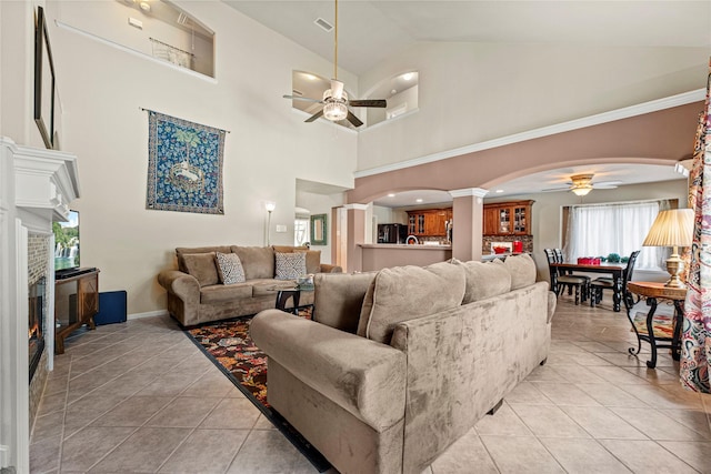 2218 Lashley Ct, Katy, TX 77450 - living area with ceiling fan, decorative columns, arched walkways, a lit fireplace, and light tile patterned flooring