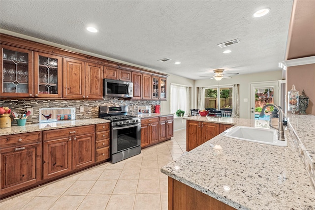 2218 Lashley Ct, Katy, TX 77450 - kitchen with stainless steel appliances, light tile patterned floors, backsplash, brown cabinets, and recessed lighting