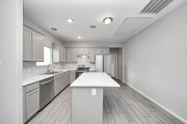 9805 Kerr, Houston, TX 77029 - kitchen featuring gray cabinetry, a kitchen island, appliances with stainless steel finishes, decorative backsplash, and recessed lighting