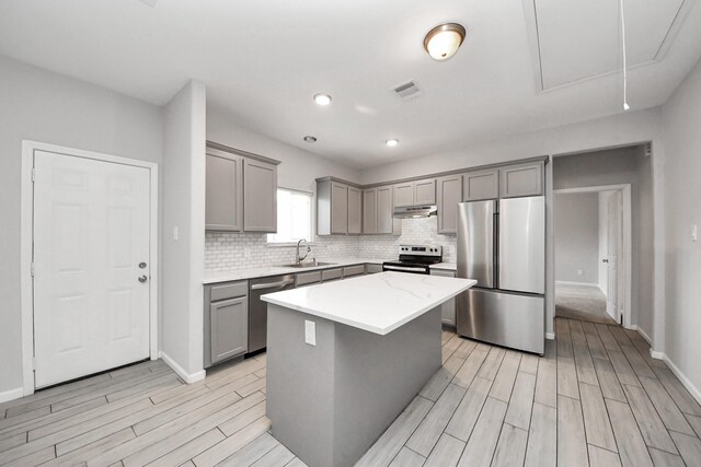 9805 Kerr, Houston, TX 77029 - kitchen featuring gray cabinets, appliances with stainless steel finishes, light wood-style floors, decorative backsplash, and recessed lighting