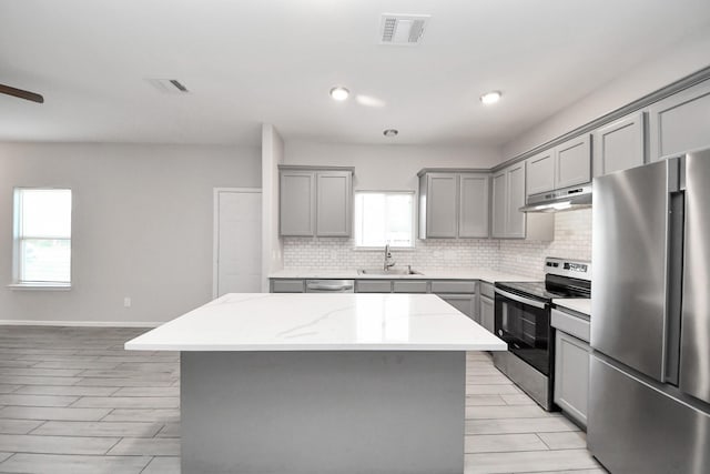 9805 Kerr, Houston, TX 77029 - kitchen with gray cabinetry, appliances with stainless steel finishes, healthy amount of natural light, decorative backsplash, and recessed lighting