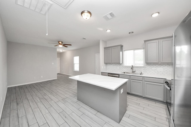 9805 Kerr, Houston, TX 77029 - kitchen with gray cabinetry, appliances with stainless steel finishes, a center island, decorative backsplash, and a ceiling fan