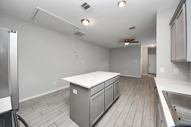 9805 Kerr, Houston, TX 77029 - kitchen featuring gray cabinetry, light wood-style floors, a ceiling fan, a center island, and stove