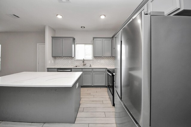 9805 Kerr, Houston, TX 77029 - kitchen featuring gray cabinets, freestanding refrigerator, backsplash, black range with electric stovetop, and recessed lighting