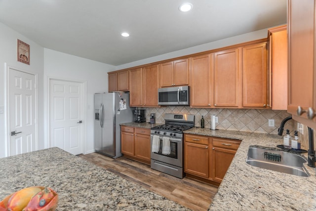 3618 Avalon Spring Ln, Spring, TX 77386 - kitchen featuring appliances with stainless steel finishes, wood finished floors, decorative backsplash, light stone countertops, and recessed lighting