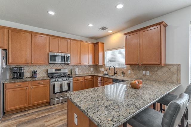 3618 Avalon Spring Ln, Spring, TX 77386 - kitchen with appliances with stainless steel finishes, light wood-style floors, a peninsula, a breakfast bar area, and recessed lighting