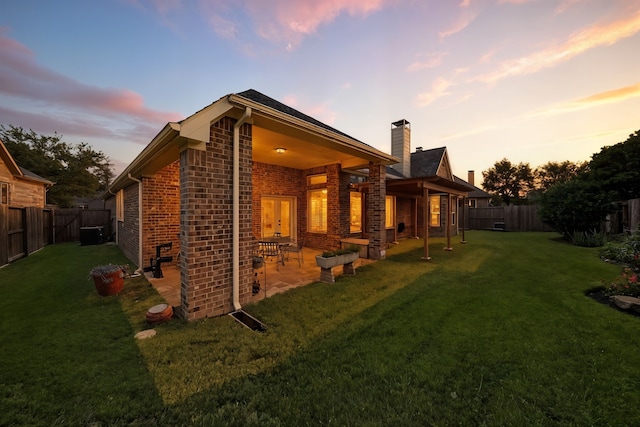 4118 Sage Brush Ct, Manvel, TX 77578 - back of house at dusk with brick siding, a fenced backyard, a patio area, and a chimney