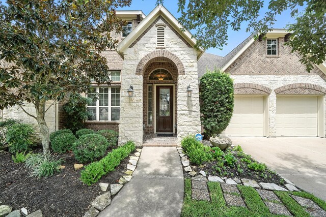 4118 Sage Brush Ct, Manvel, TX 77578 - view of exterior entry featuring brick siding, a garage, driveway, and stone siding