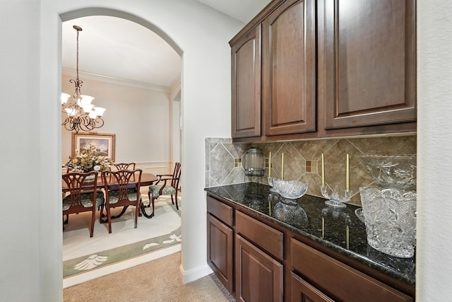 4118 Sage Brush Ct, Manvel, TX 77578 - kitchen featuring arched walkways, light colored carpet, dark stone countertops, decorative backsplash, and dark brown cabinets