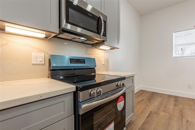9727 Cargill St Unit A, Houston, TX 77029 - kitchen with appliances with stainless steel finishes, light wood-style flooring, gray cabinets, and light stone counters