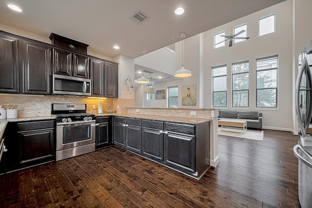 9027 Laverne Cres, Houston, TX 77080 - kitchen with appliances with stainless steel finishes, dark wood-style flooring, a peninsula, light stone counters, and recessed lighting