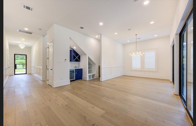3909 Ella Blvd, Houston, TX 77018 - unfurnished living room with light wood-type flooring, a dry bar, a decorative wall, a wainscoted wall, and a chandelier