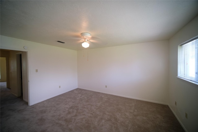 spare room featuring ceiling fan and dark colored carpet