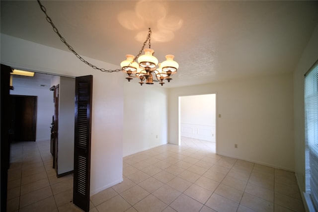 tiled spare room with an inviting chandelier