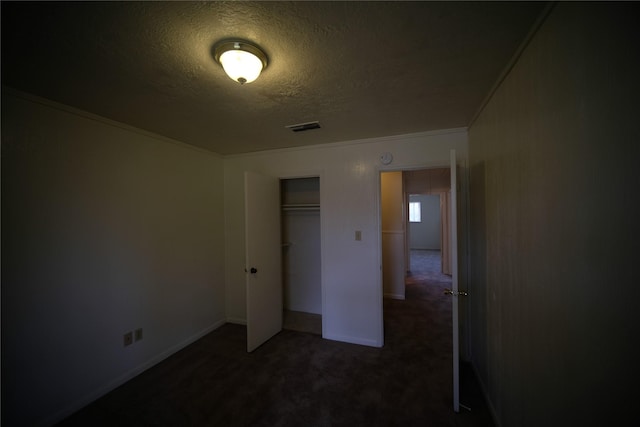 unfurnished bedroom featuring a closet, dark colored carpet, and a textured ceiling