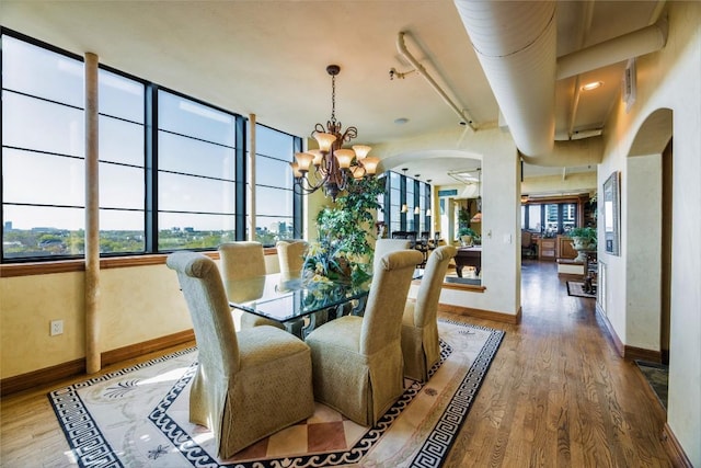 dining room with hardwood / wood-style floors, a high ceiling, and an inviting chandelier