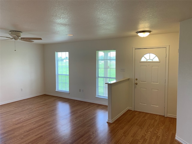 entryway featuring ceiling fan, plenty of natural light, hardwood / wood-style flooring, and a textured ceiling