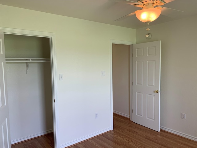 unfurnished bedroom featuring ceiling fan, a closet, and dark wood-type flooring