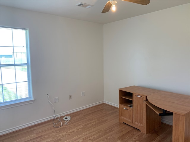 unfurnished office with plenty of natural light, hardwood / wood-style flooring, and ceiling fan