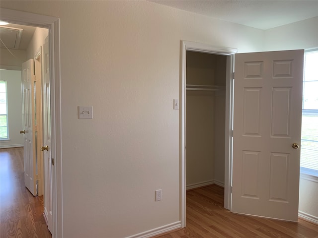 unfurnished bedroom featuring wood-type flooring, a closet, and multiple windows