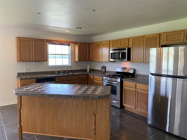 kitchen with a center island, sink, tile counters, and stainless steel appliances