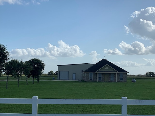 view of front facade featuring a garage, a front lawn, and a rural view