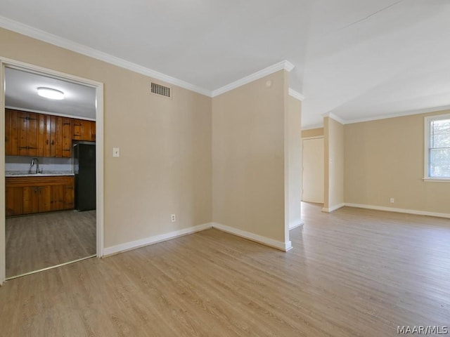 empty room with crown molding, sink, and light hardwood / wood-style flooring