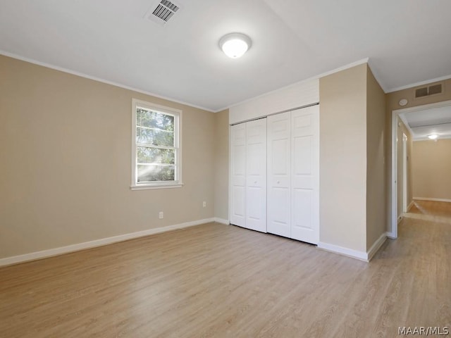 unfurnished bedroom with a closet, ornamental molding, and light hardwood / wood-style floors