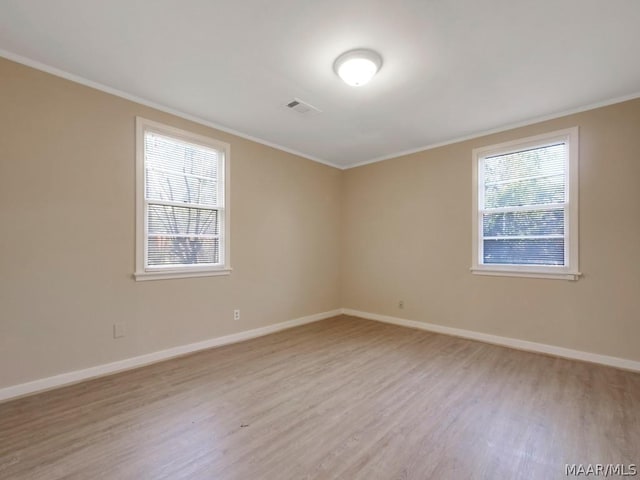 empty room with ornamental molding and light wood-type flooring