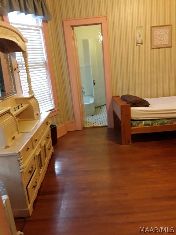 bedroom with dark hardwood / wood-style flooring, connected bathroom, and multiple windows