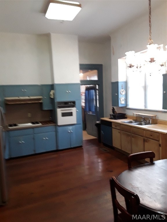 kitchen with oven, hanging light fixtures, dark hardwood / wood-style floors, sink, and a chandelier