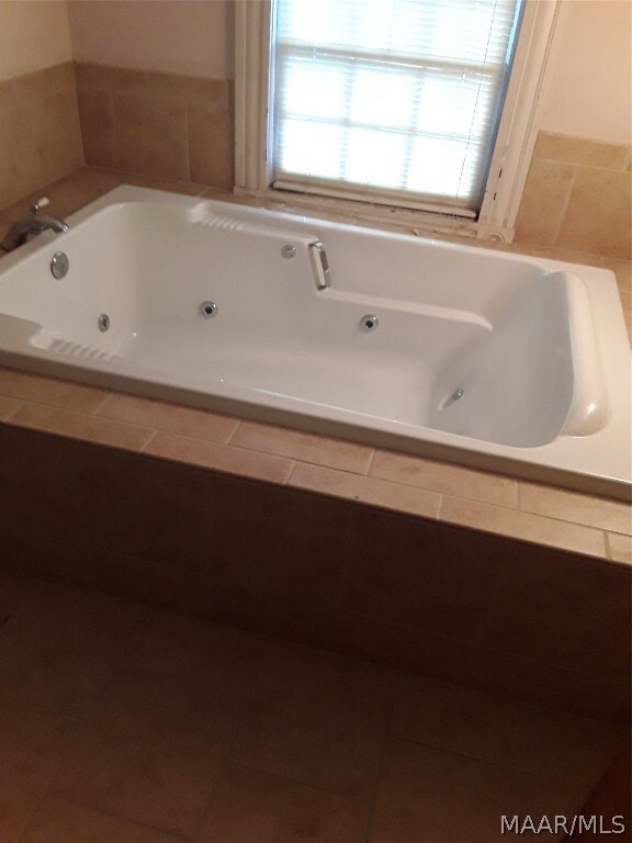 bathroom with tile flooring and a relaxing tiled bath