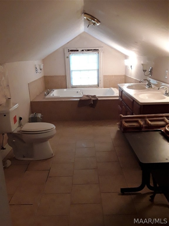 bathroom featuring lofted ceiling, toilet, a washtub, and tile floors
