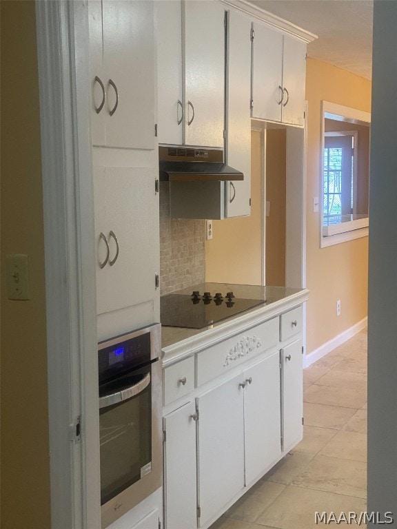 kitchen featuring stainless steel oven, white cabinetry, light tile floors, and black electric cooktop