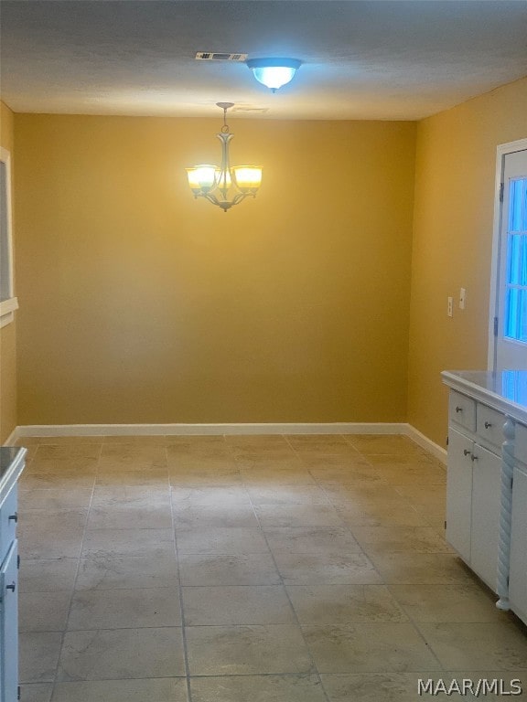 spare room with light tile flooring and a notable chandelier