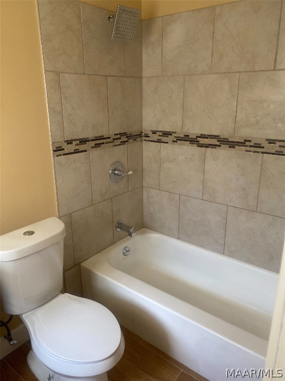 bathroom featuring toilet and tiled shower / bath combo