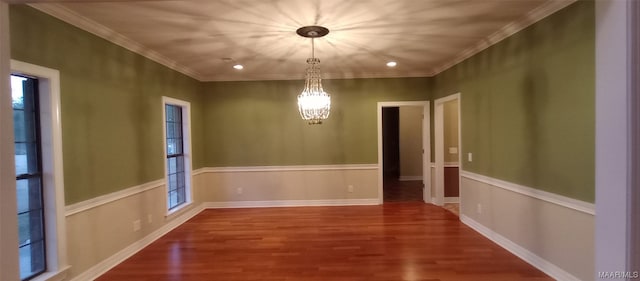 empty room featuring crown molding, an inviting chandelier, and dark wood-type flooring