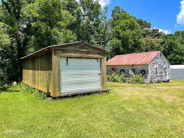 view of outdoor structure featuring a lawn and a garage