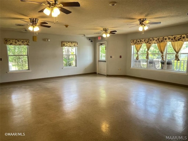 unfurnished room with a textured ceiling, ceiling fan, and a healthy amount of sunlight