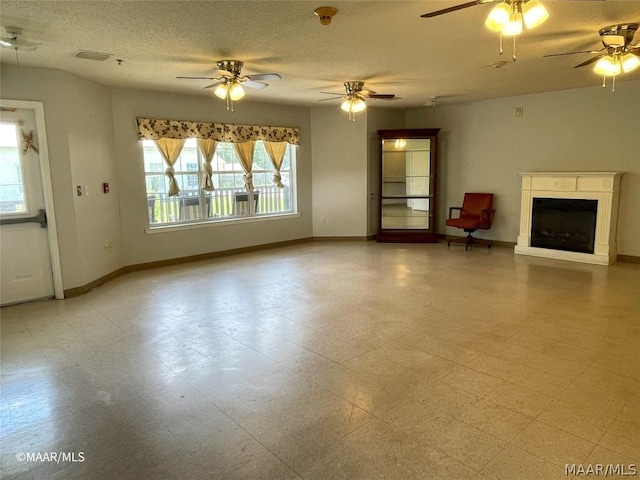 unfurnished living room with ceiling fan, light tile flooring, and a textured ceiling