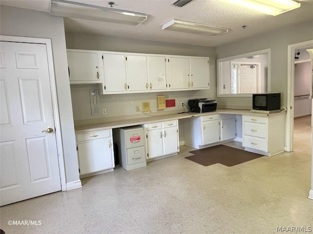 kitchen featuring white cabinets and a textured ceiling