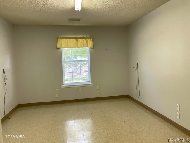 empty room with light tile floors and a textured ceiling