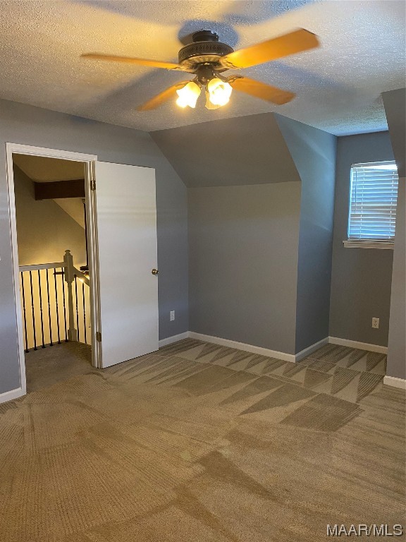 bonus room featuring ceiling fan, lofted ceiling, dark carpet, and a textured ceiling