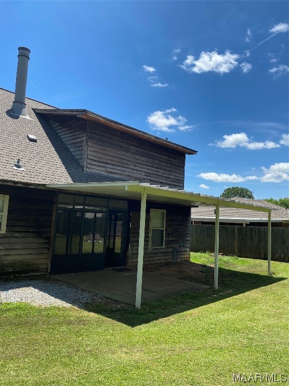 back of house with a lawn and a patio