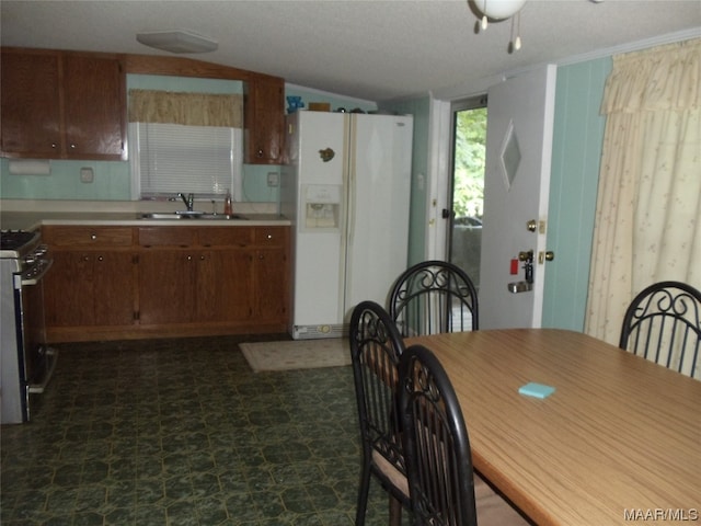 tiled dining area with ceiling fan, lofted ceiling, and sink